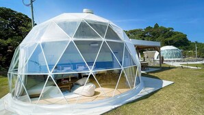 A geodesic dome structure with a transparent roof, a small interior space with a bed and a table, and a white exterior. - TOIGLAM solasita (Kushima)