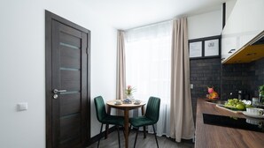 Una cucina piccola e moderna con zona pranzo, una porta in legno e una finestra con tende.