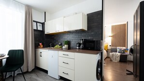 Una cucina compatta con mobili bianchi, una parete a schiena d'oca nera, una macchina da caffè e un forno a microonde.