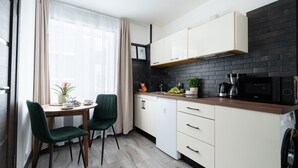 Una cucina moderna con mobili bianchi, uno schienale in mattoni neri e un'area pranzo con tavolo e sedie.