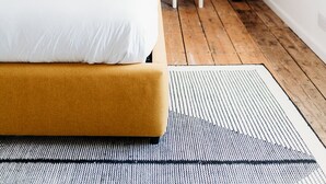 Ein Schlafzimmer mit einem Bett, einem Nachttisch, einer Lampe und einer Wandleuchte.