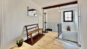 A wooden bench, a small potted plant, a coat rack, and a staircase with a railing. - Casa Matilde Apartments (Gambarogno)