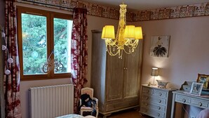 Ein Schlafzimmer mit einem Bett, einem Holzschrank, einem Schreibtisch und einer Pendelleuchte.