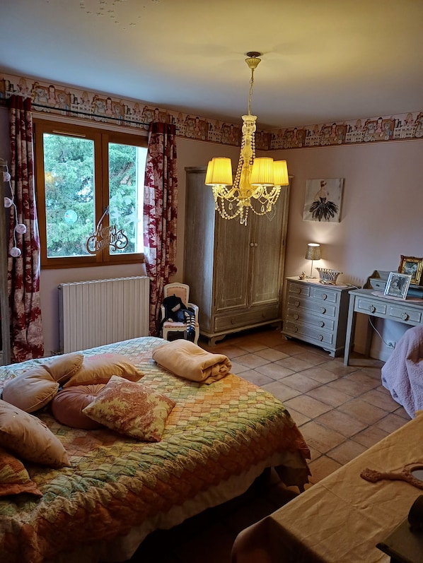 Une chambre à coucher avec un lit, une armoire en bois, un bureau et un lustre.