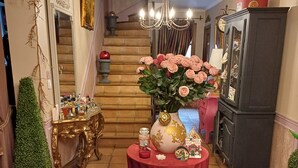 Ein stilvoll eingerichteter Innenraum mit einer Treppe, einer Chandelüster, einem Tisch mit Blumen und einem Hund, der auf dem Boden liegt.