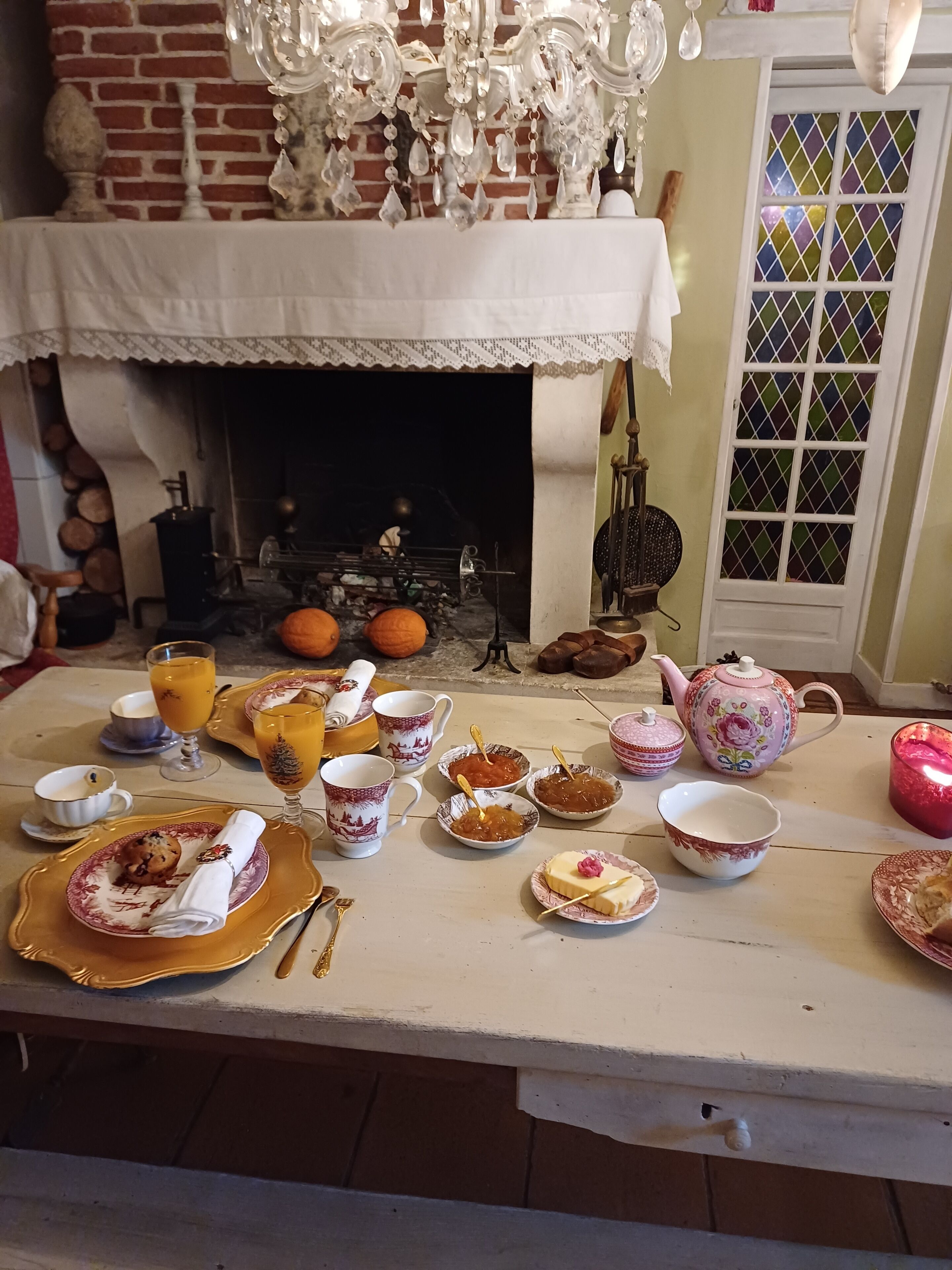 Una mesa de comedor dispuesta con varios platos, una chimenea y una ventana con un diseño colorido.