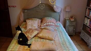Een bed met een gewatteerd sprei, een decoratief hoofdbord en een kroonluchter.