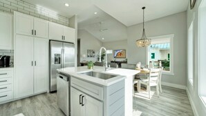 A modern kitchen with white cabinetry, a stainless steel refrigerator, and a built-in dishwasher.