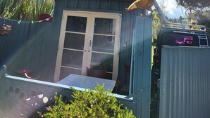 A small, rustic building with a red roof and a circular window. It has a door and a small porch area. - TIny House experience, Lake Rotoiti, Rotorua (Rotoiti Forest)