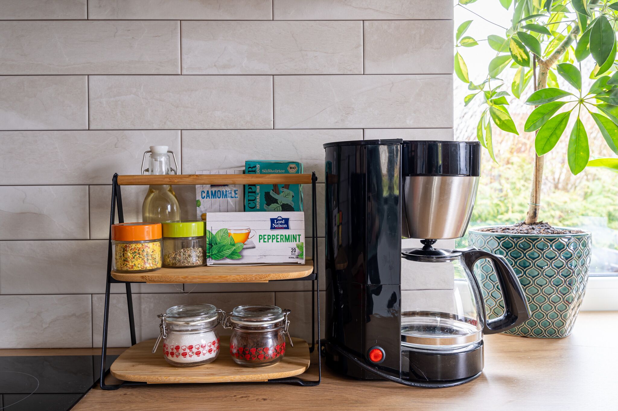 Un plan de travail de cuisine avec une machine à café, des pots à épices et une boîte de capsules de café.