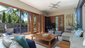 A modern living room with a large TV, comfortable seating, and a view of the outdoors.