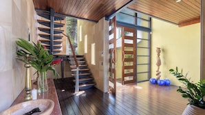 A modern interior with a wooden staircase, a large window, and a wooden floor.