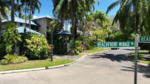 A street sign for Beachfront Mirage Drive, surrounded by lush greenery and a modern building.