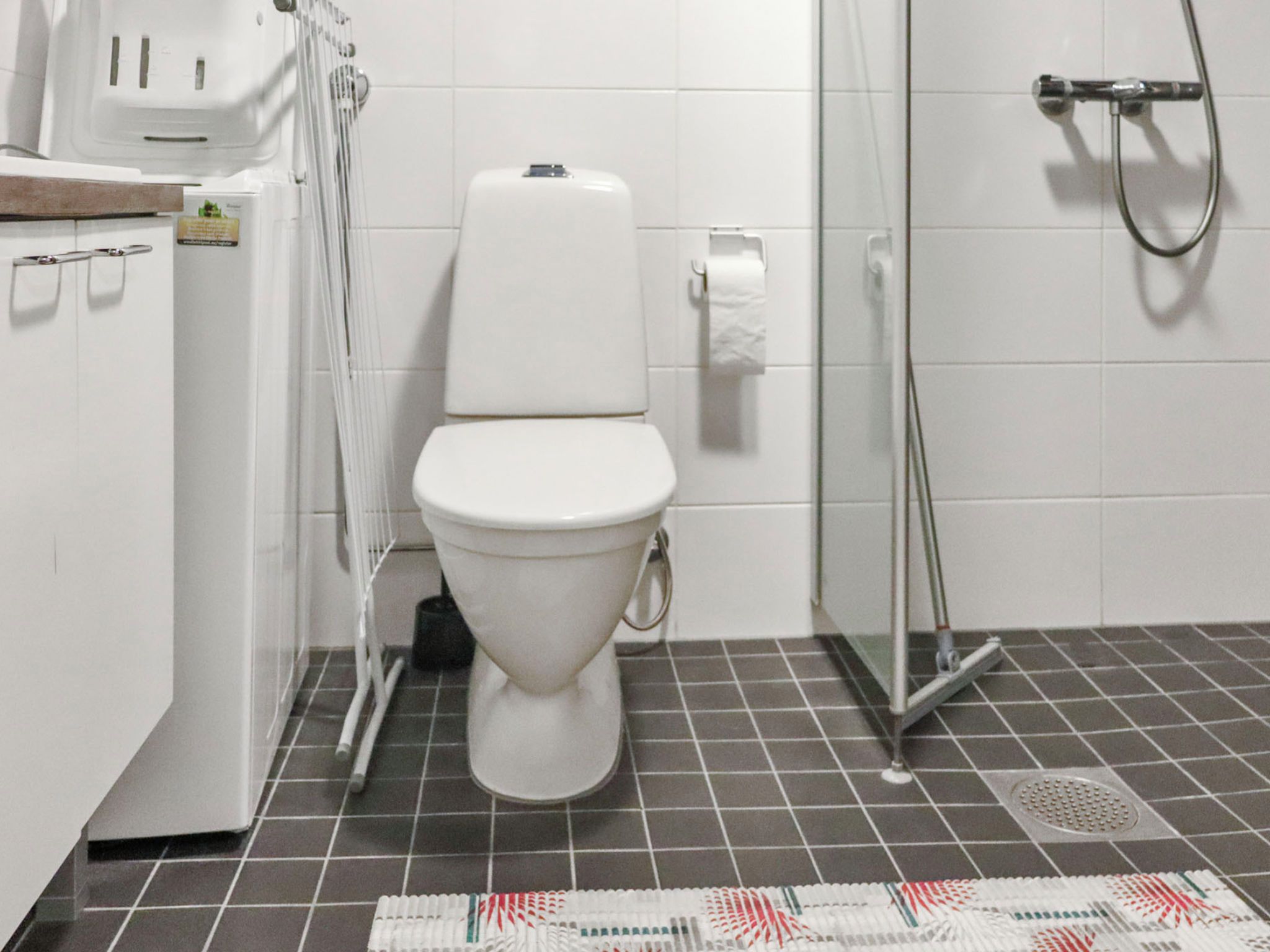 A bathroom with a white toilet, a shower, and a tiled floor.