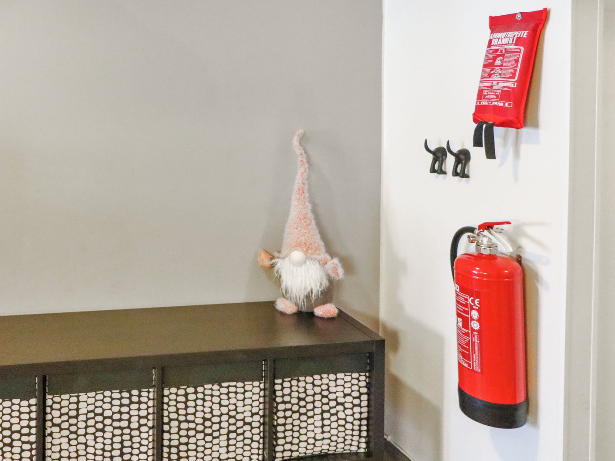 Een tuinmannetje op een tafel, een brandblusser en twee kleine beeldjes aan de muur.