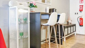 A modern kitchen with a refrigerator, bar stools, a sink, and a fire extinguisher.