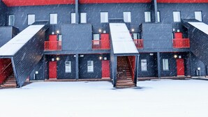 A multi-story building with red railings and a snow-covered ground.