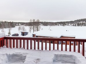 Un paysage enneigé avec une terrasse en bois et une vue sur des maisons et des arbres.