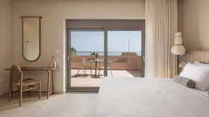 A hotel room with a bed, a desk, a chair, a large window with a view of the sea, and a balcony with outdoor furniture. - Villa Agali Free* heated pool & 70m to Sea! (Chania)