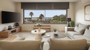 A modern living room with a large TV, comfortable seating, a coffee table, and a view of the beach. - Villa Agali Free* heated pool & 70m to Sea! (Chania)
