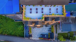 An aerial view of a hotel with a rooftop parking area, outdoor seating, and a landscaped garden. - Hotel Hidden Kingdom (Pokhara)