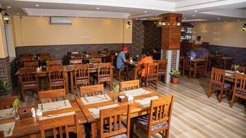 Un restaurante con mesas y sillas de madera, una pared de ladrillo y una zona de bar.
