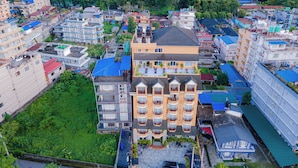 A multi-story hotel with balconies, a central courtyard, and a river in the background. - Hotel Hidden Kingdom (Pokhara)