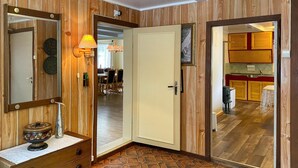 Une pièce aux murs lambrissés, avec une porte donnant sur un espace cuisine.