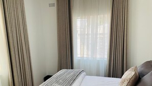 A hotel room with a bed, curtains, and a window. - Immaculate Home in Avondale West - 2166 (Harare)