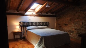 Ein Schlafzimmer mit Holzboden, einem Bett mit gemustertem Kopfteil, einer Nachttischlampe und einer Steinwand.