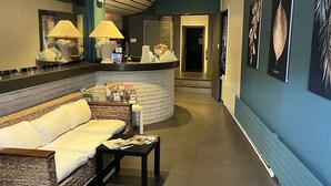 A modern lobby with a curved reception desk, a wicker sofa, and a small table with magazines.