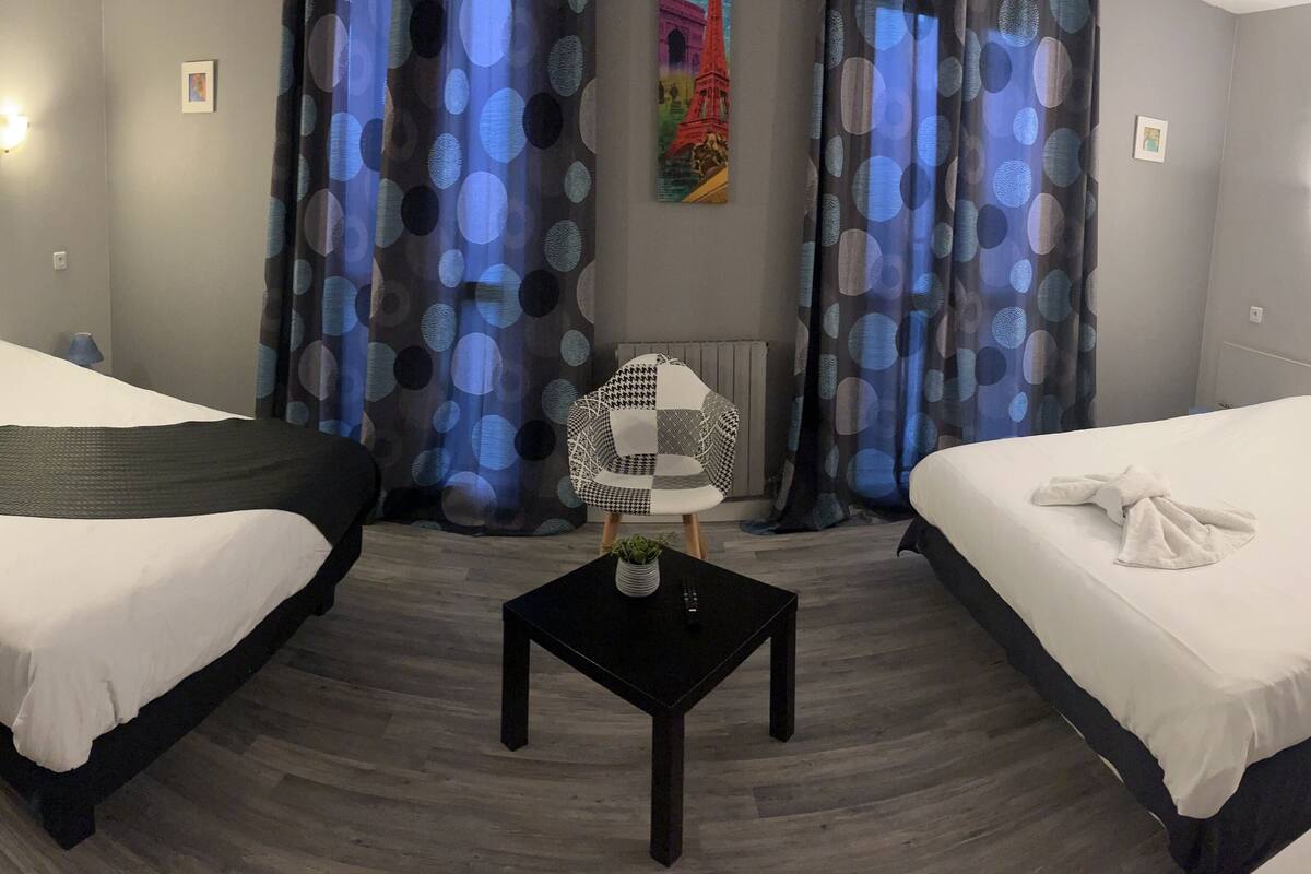 A hotel room with two beds, a small table with a plant, and a wall-mounted TV.