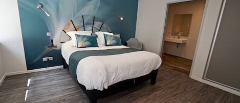 Un dormitorio moderno con una cama grande, un mural en la pared y un baño visible a través de una puerta abierta.