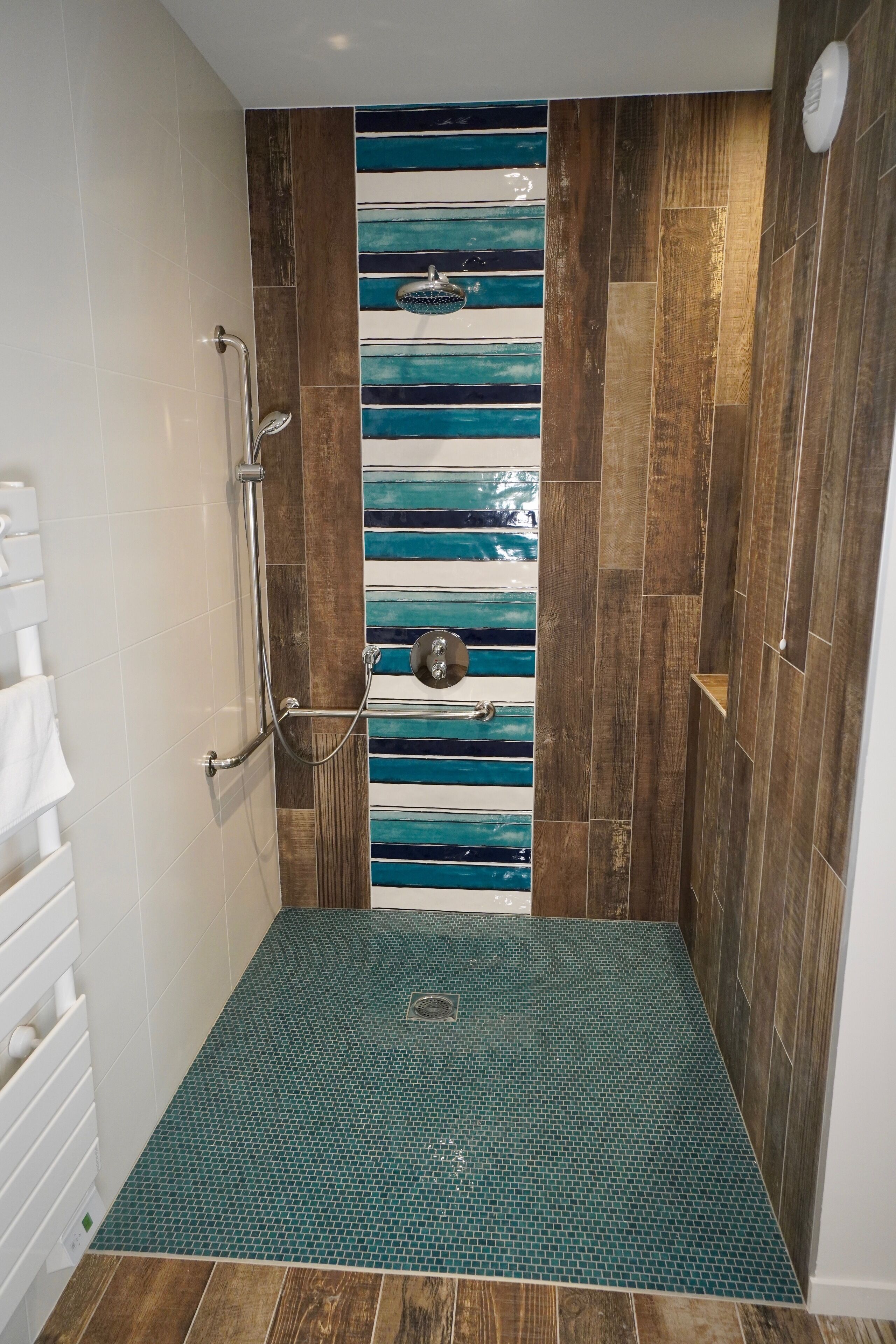 Ducha con pared de madera y diseño de azulejos azules y blancos a rayas.