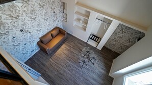 A spacious room with a wooden floor, a brown sofa, and a ceiling fan.