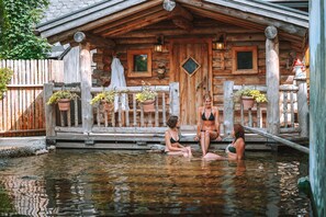 Een houten chalet met een houten terras en potplanten.