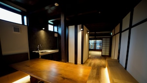A wooden table with benches in a dimly lit room with traditional Japanese sliding doors and a visible sink.