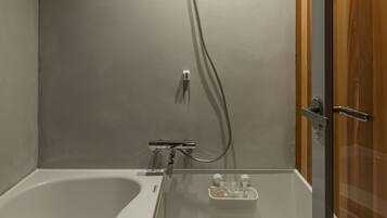 A modern bathroom with a bathtub, shower, and toilet.