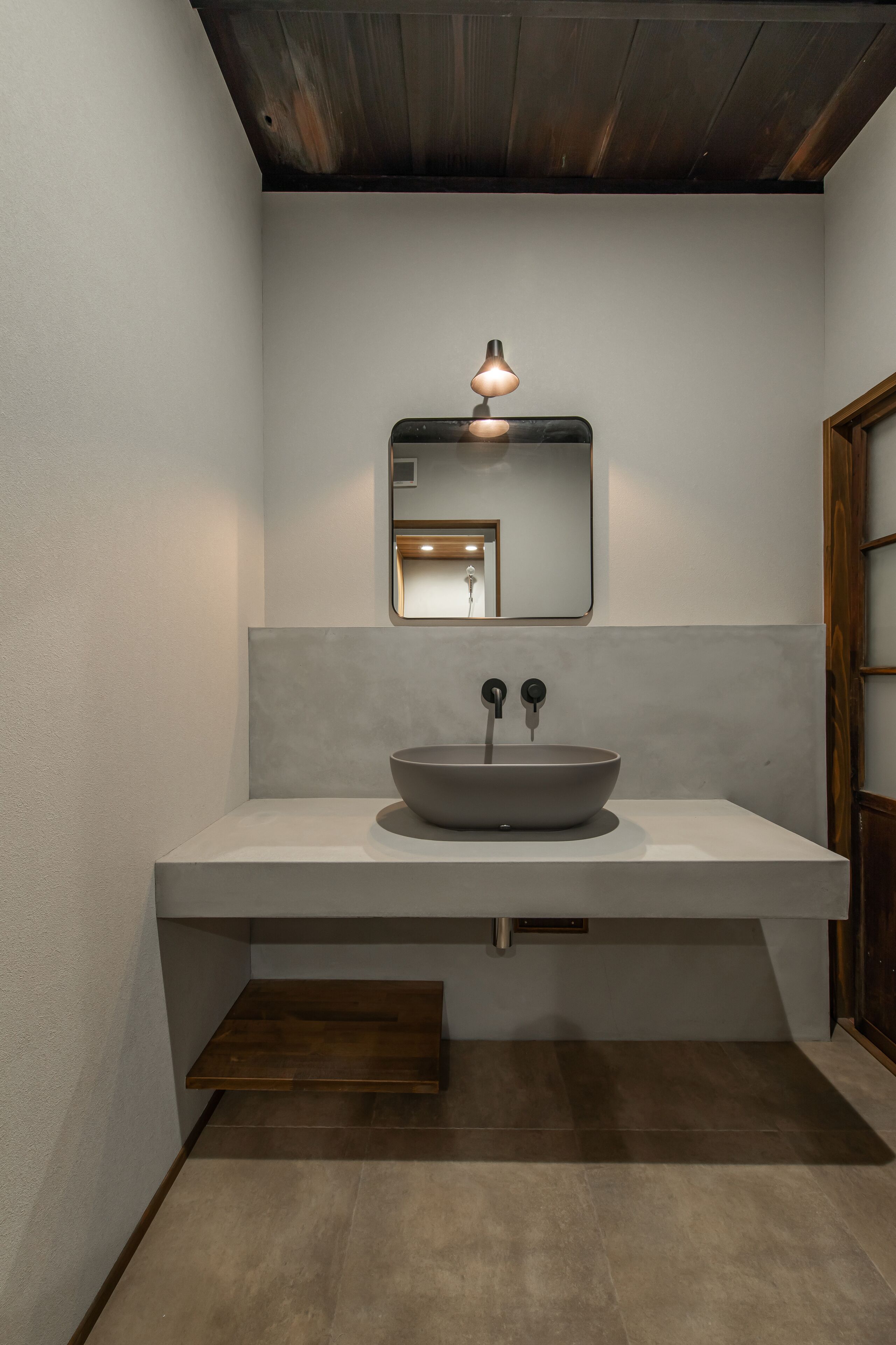 Un baño moderno con un espejo grande, un lavabo sobre encimera y un techo de madera.