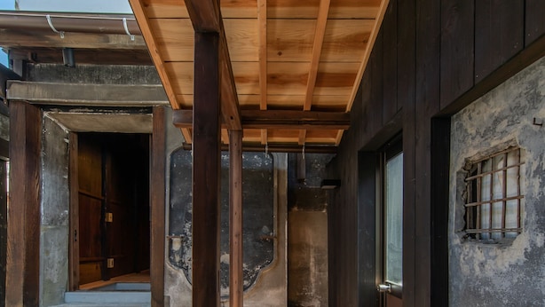 A wooden interior corridor with a sloped ceiling and a view of a traditional Japanese building.