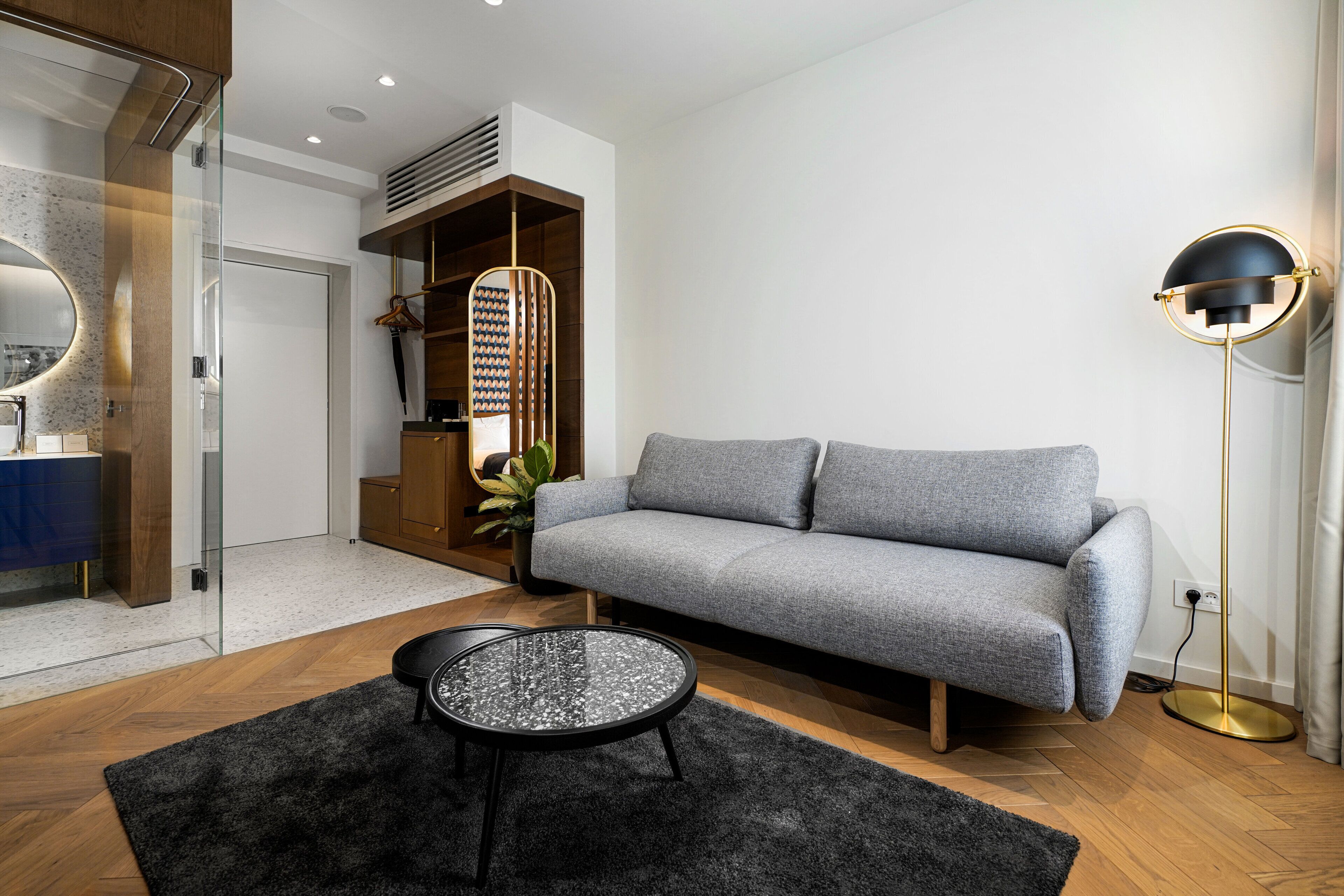 A modern living room with a grey sofa, a round coffee table, and a floor lamp.