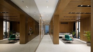 A modern interior with a central corridor, wooden paneling, and seating areas with green chairs. - Dominic Smart & Luxury Suites - Edition (Belgrade)