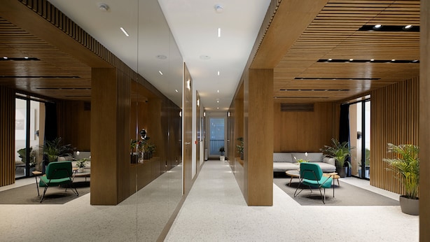 A modern interior with a central corridor, wooden paneling, and seating areas with green chairs. - Dominic Smart & Luxury Suites - Edition (Belgrade)