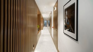A modern hallway with wooden paneling on one side, a framed picture on the wall, and a potted plant. - Dominic Smart & Luxury Suites - Edition (Belgrade)