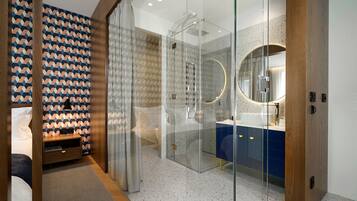 Een moderne badkamer met een douchecabine van glas, een ronde spiegel en een blauwe wastafelmeubel.