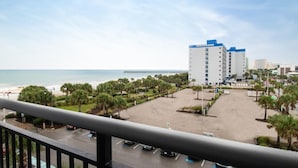 Een hotel met een parkeerplaats, uitzicht op het strand en palmbomen.