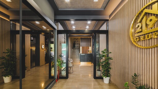 Eine moderne Hotelhalle mit Empfangsbereich, Treppe und Zimmerpflanzen.