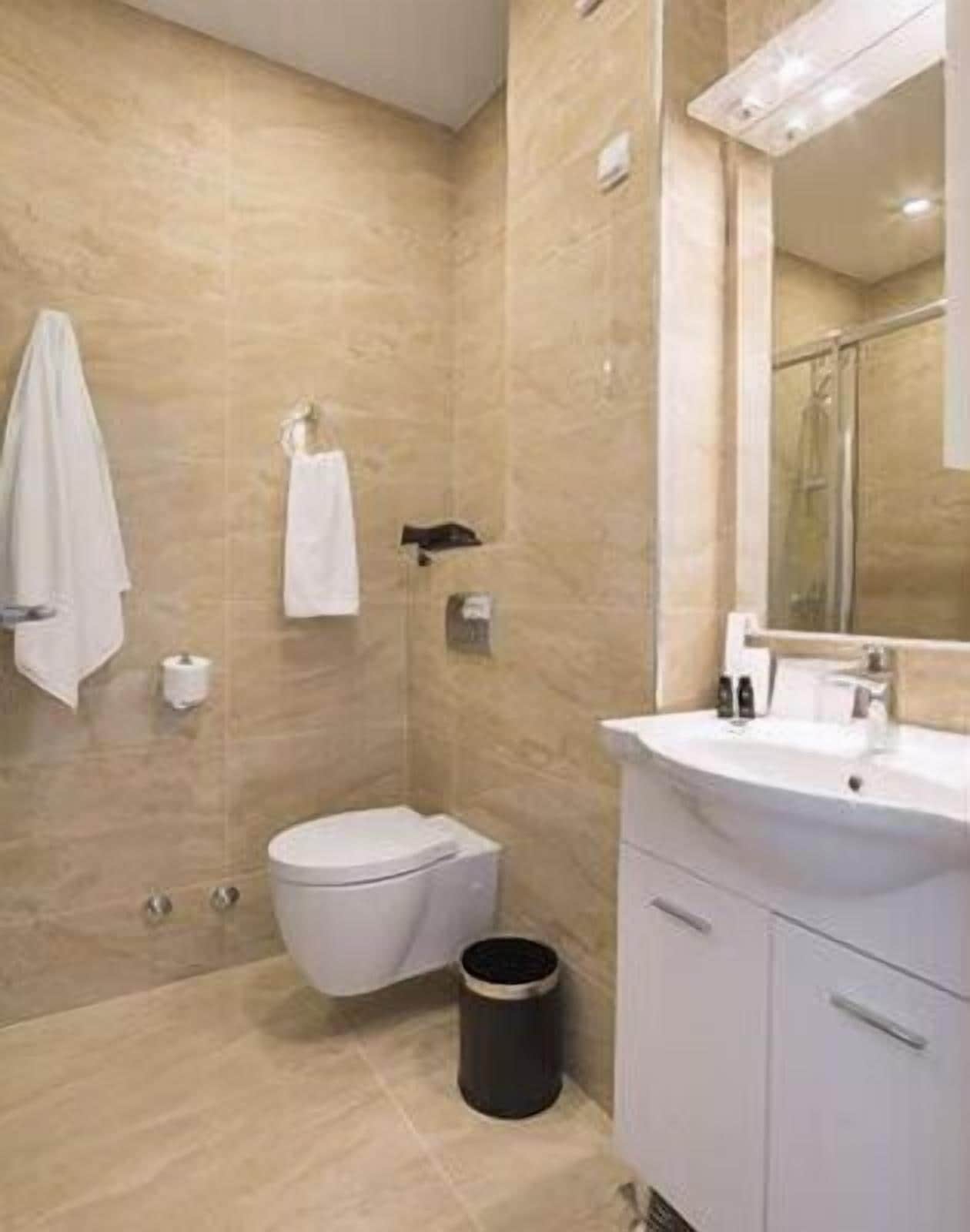 A modern bathroom with a toilet, sink, and mirror.