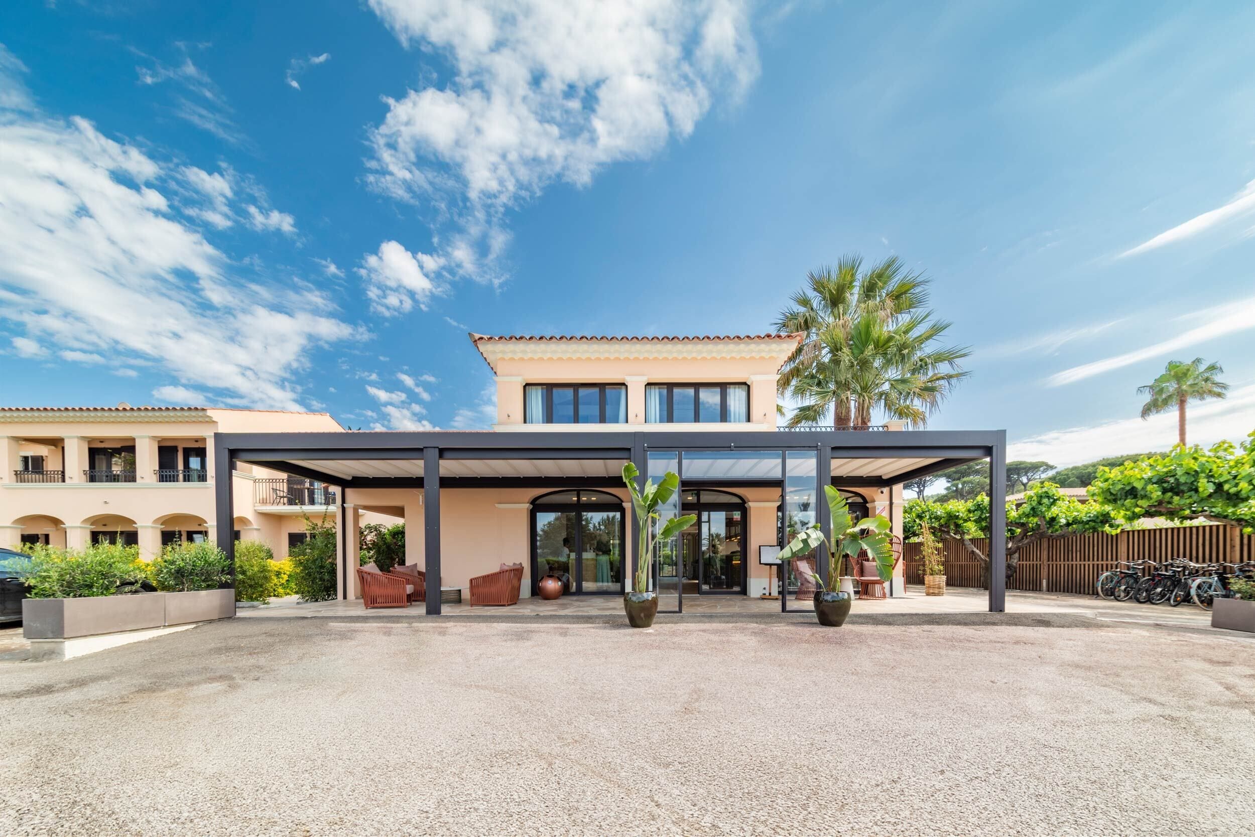 Un hotel moderno con ingresso coperto, posti a sedere all'aperto e un'area di parcheggio.
