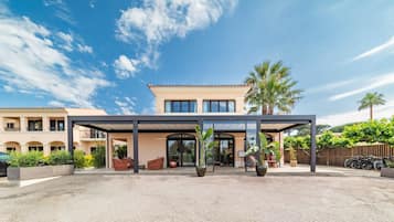 Un hotel moderno con entrada cubierta, mobiliario exterior y zona de aparcamiento.